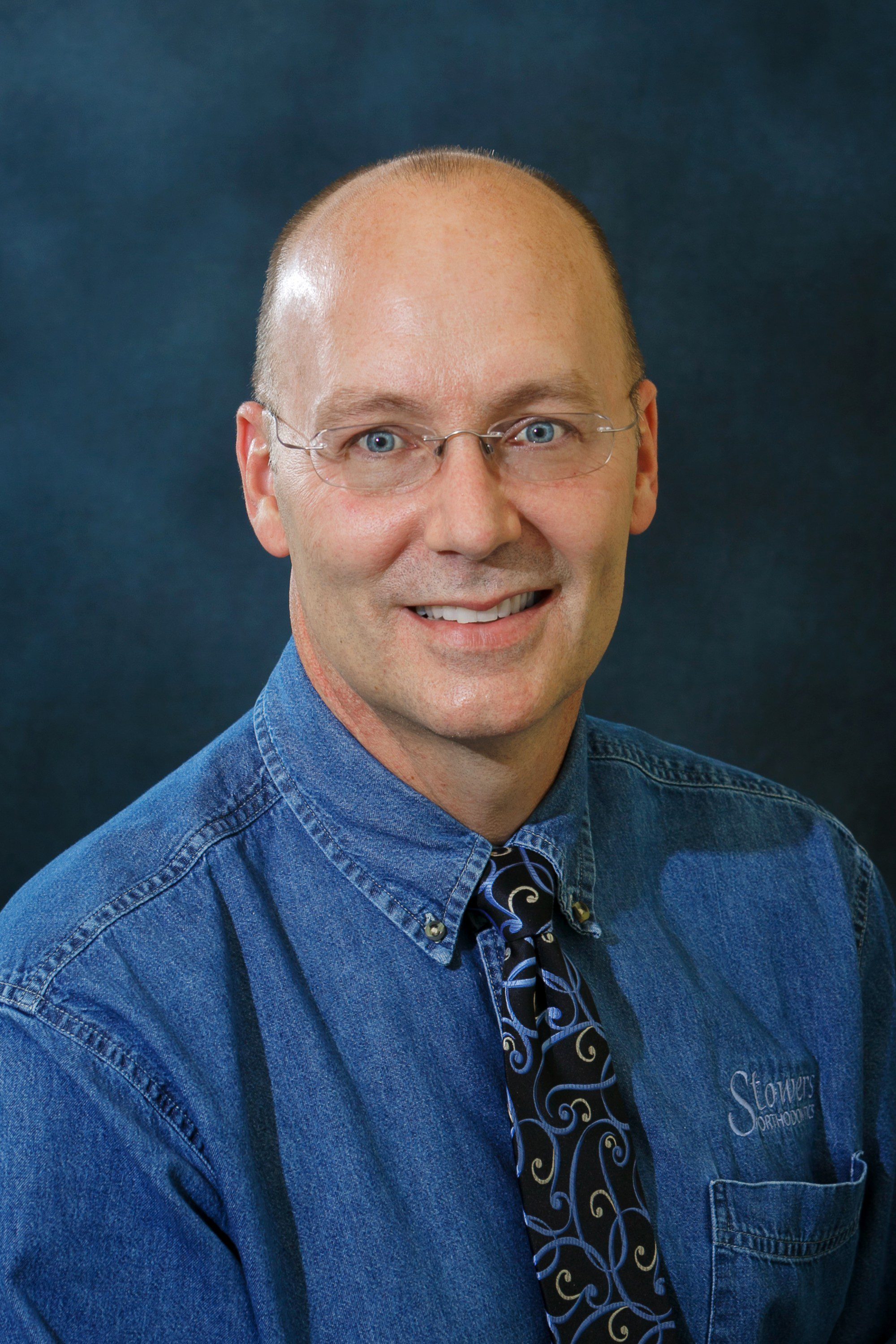 A man with bald head wearing glasses and a tie.